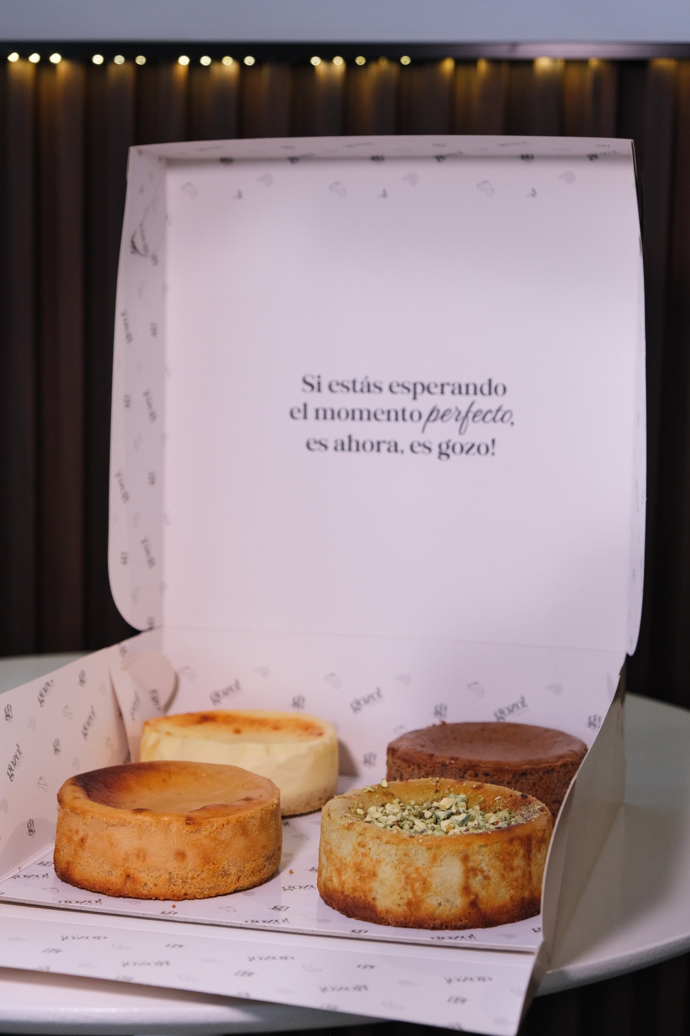 Caja abierta con tartas vascas de distintos sabores y una tarjeta con la frase de la marca